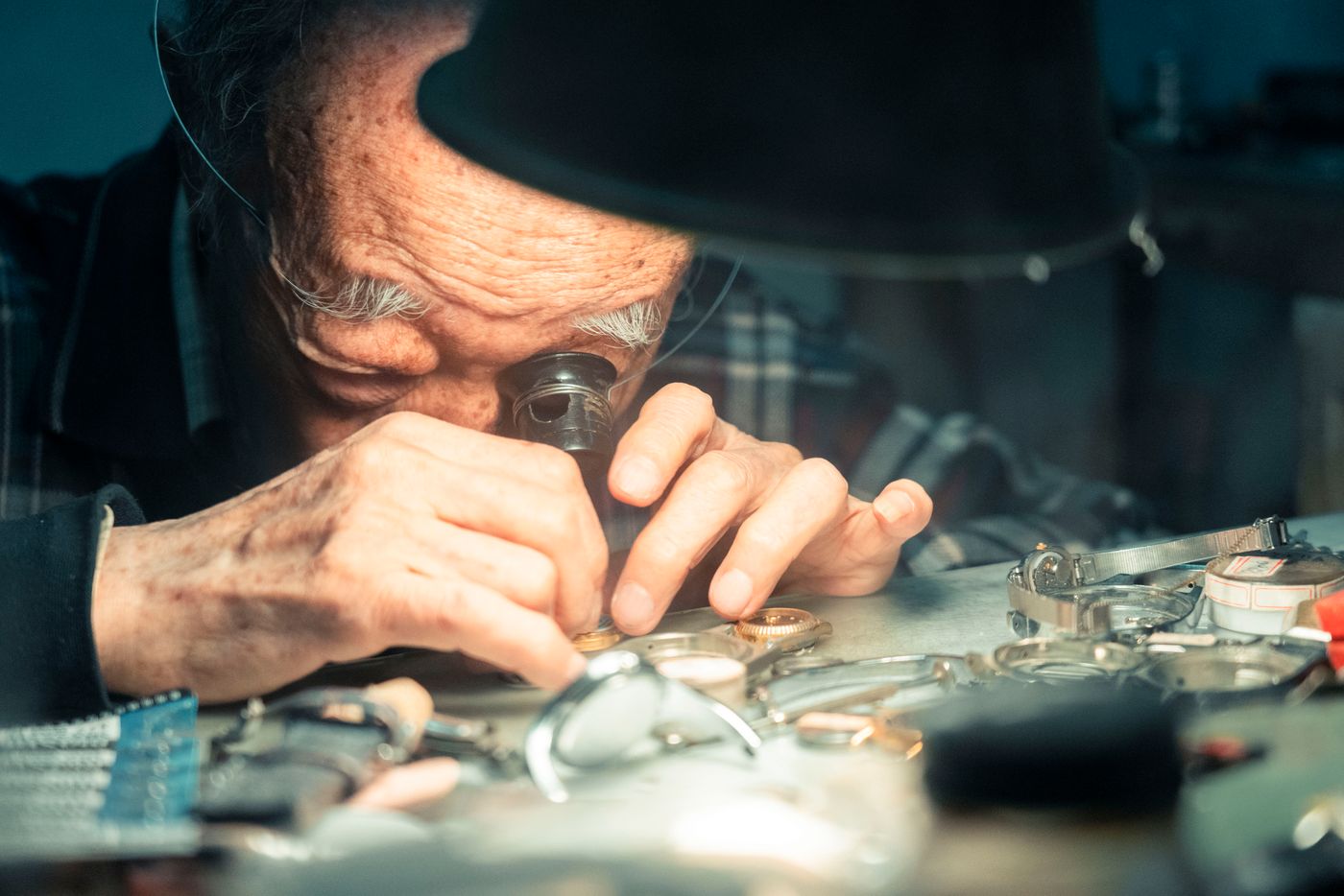 Watchmaker examining vintage wristwatches through a loupe at the bench